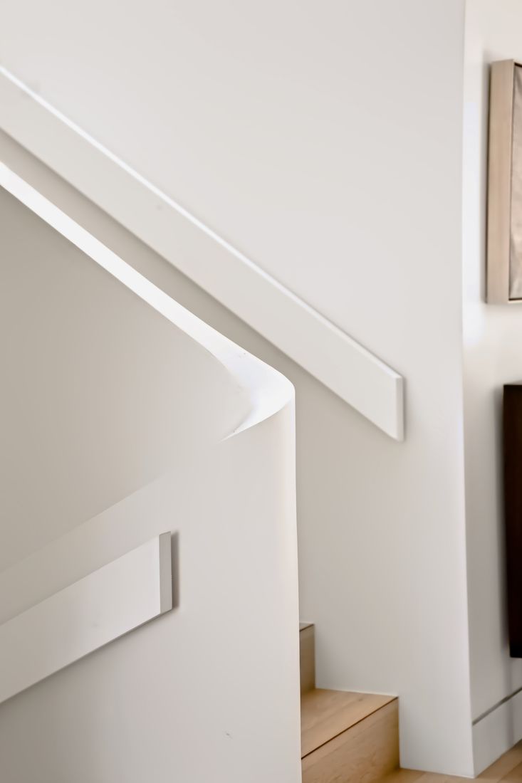 A curved white balustrade rising beside an oak floor with a curved skirting line