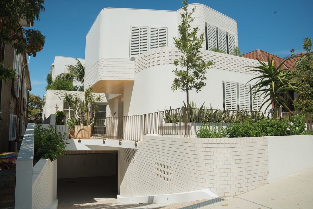 Completed white brick residence with curved masonry and timber soffit, Bondi Beach