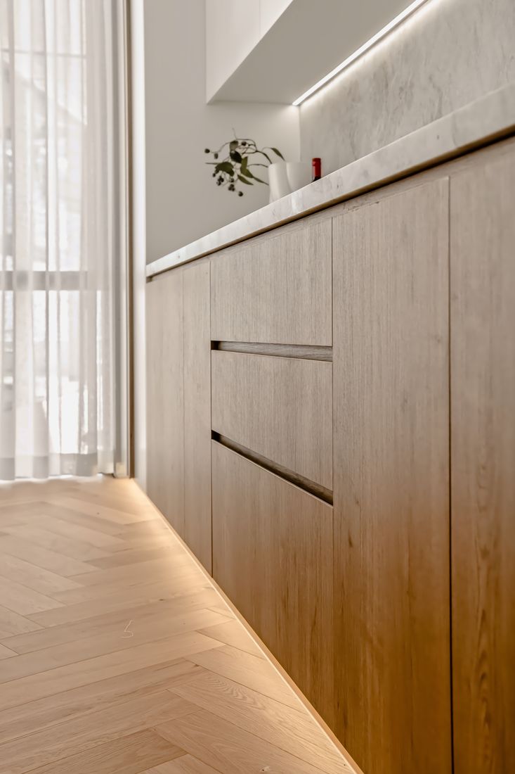 Close detail of light oak cabinetry with recessed horizontal finger pulls