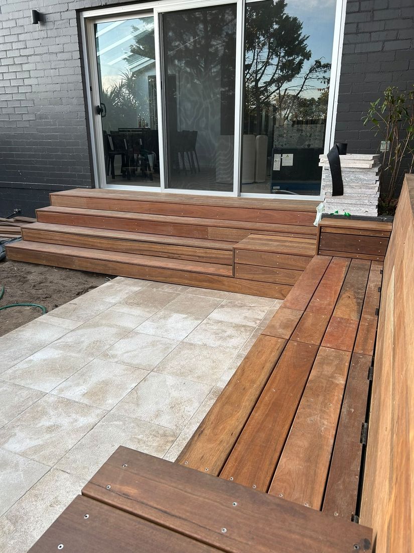 Spotted gum steps and bench seating beside natural stone tiles outside sliding doors