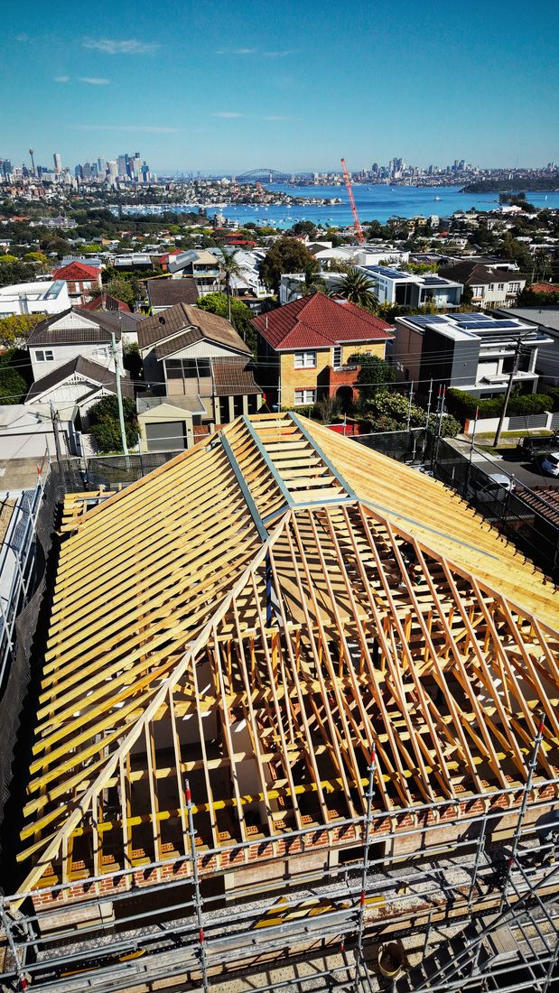 The pitched roof frame from above, looking over Dover Heights to the Sydney harbour and city