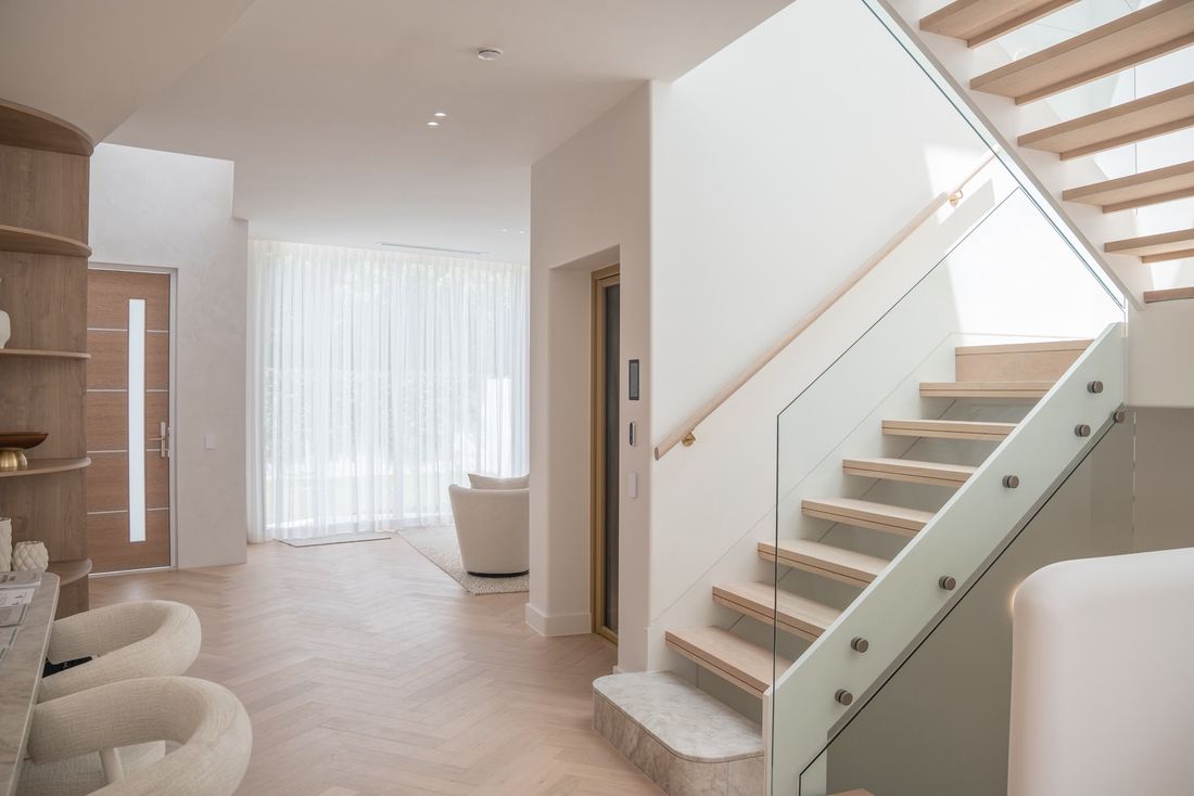 Finished entry with a light oak stair, glass balustrade and herringbone flooring