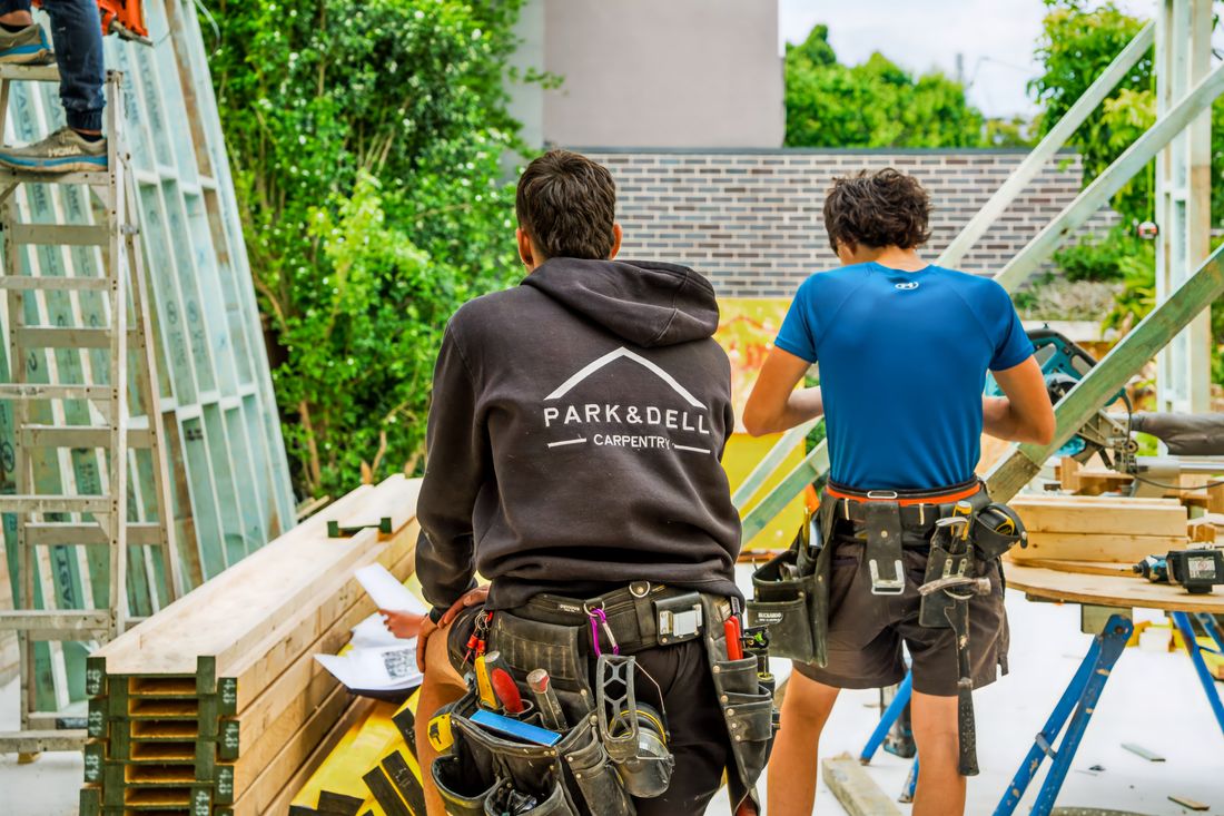 Two Park & Dell carpenters on site, tool belts on, reviewing an upcoming build
