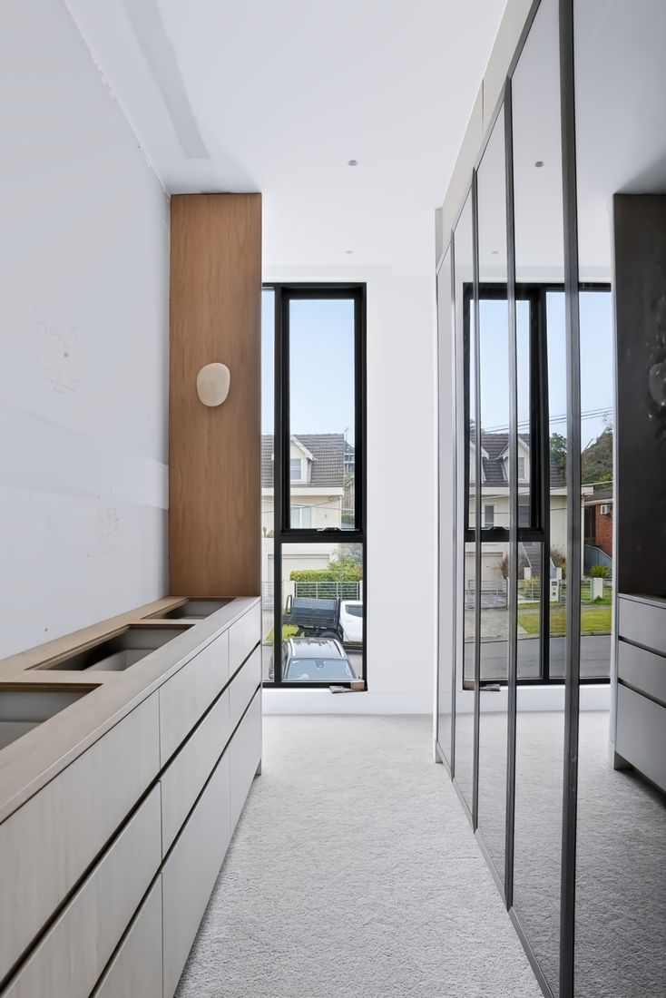 Built-in oak storage drawers running to a windowed wall, lit by a single wall sconce