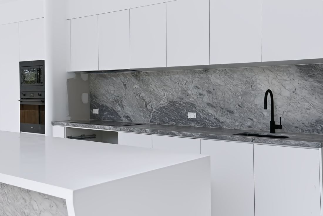 A kitchen mid-install, marble splashback fitted and carcasses open