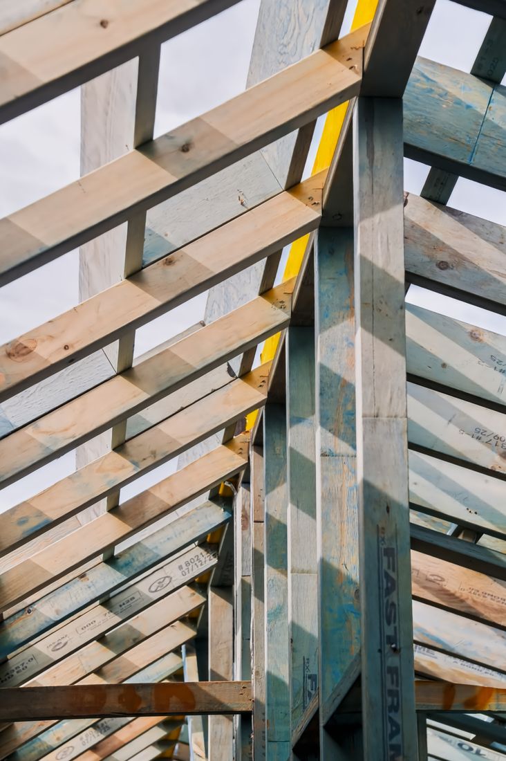 Rafters and a steel stud seen against the sky during roof framing