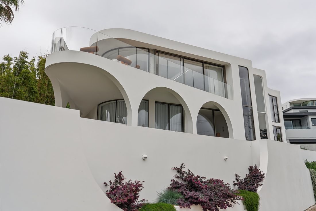 A white curved home with arched openings, finished by Park & Dell
